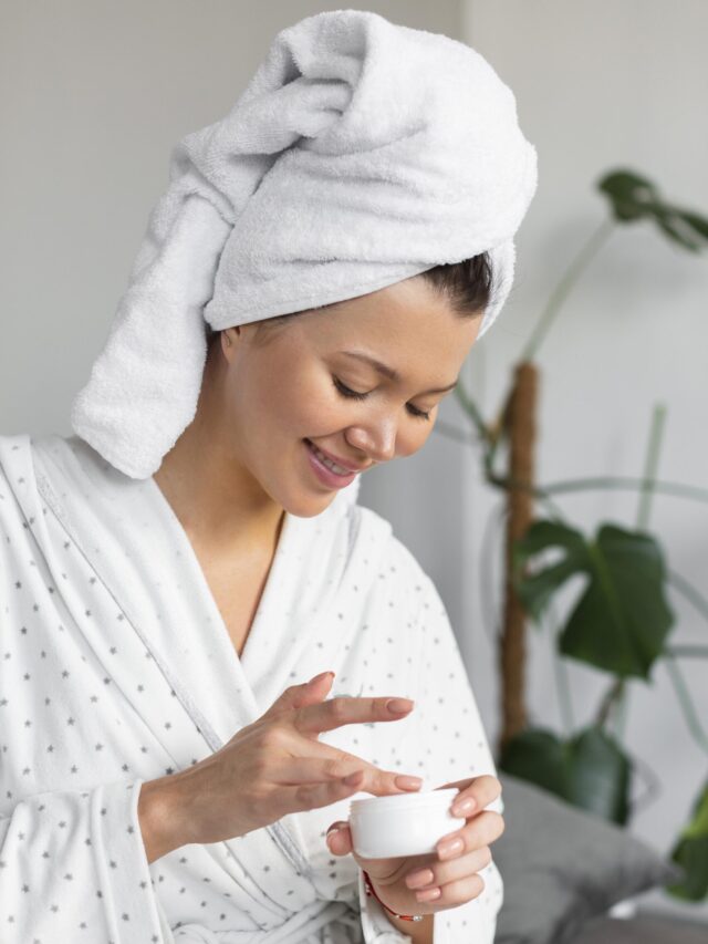 A person using a hydrating cream on damp skin.