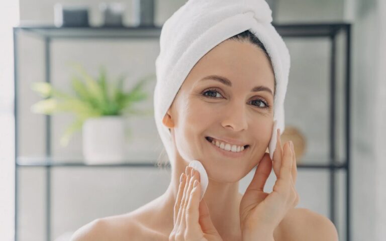 A woman applying a hydrating face serum during winter for glowing skin.