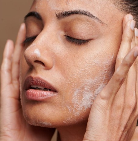A woman applying hydrating cream to hydrate skin for winter glow.