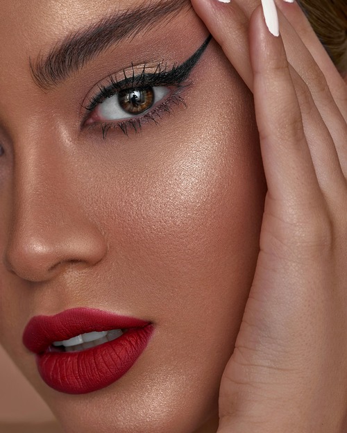 Model with luminous skin showcasing perfectly applied highlighter for a radiant festive look.